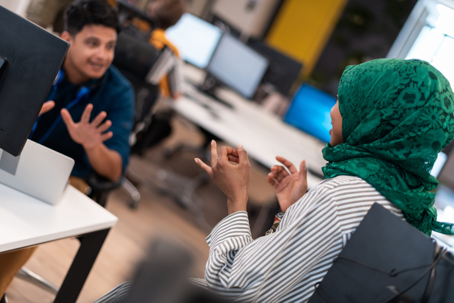 Multiethnic startup business team woman wearing a hijab on meeting in modern open plan office interior brainstorming, working on laptop and desktop computer. Selective focus